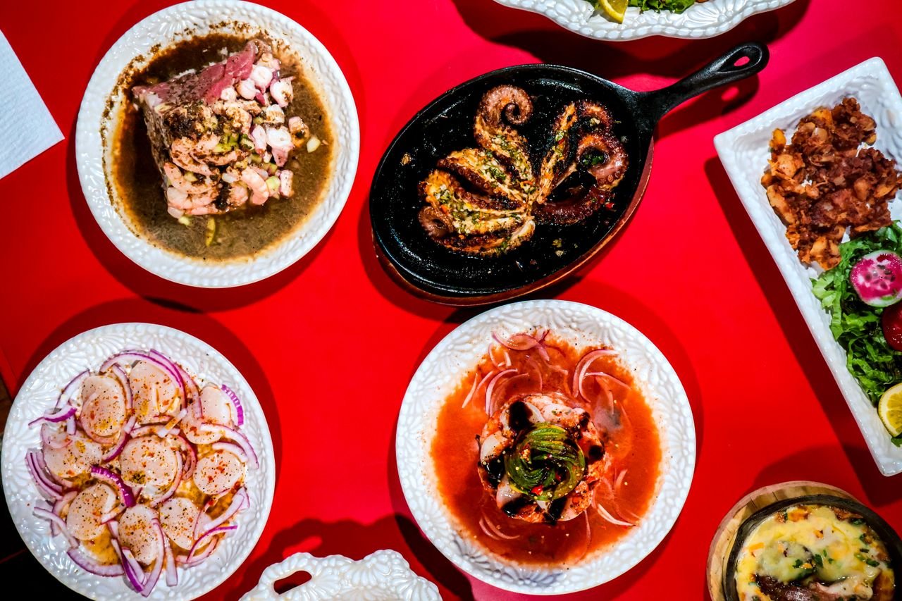 services-02 A vibrant display of authentic Mexican dishes featuring seafood and fresh ingredients on a red surface.